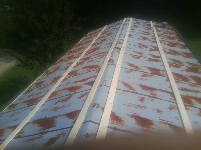Rusted metal roof panels with new wood purlins before replacement — Storm Damage Roof Repair in Blairsburg by Roofing Brothers