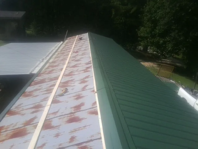 Old rusted panels beside newly installed green metal roofing — Wind Damage Roof Repair by Roofing Brothers in Blairsburg