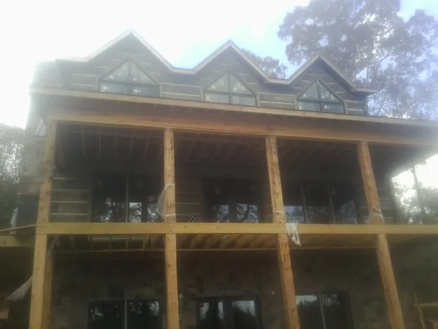 Dormers and porch framing on a large log home under construction — Roof Coating work by our crew in Blairsburg