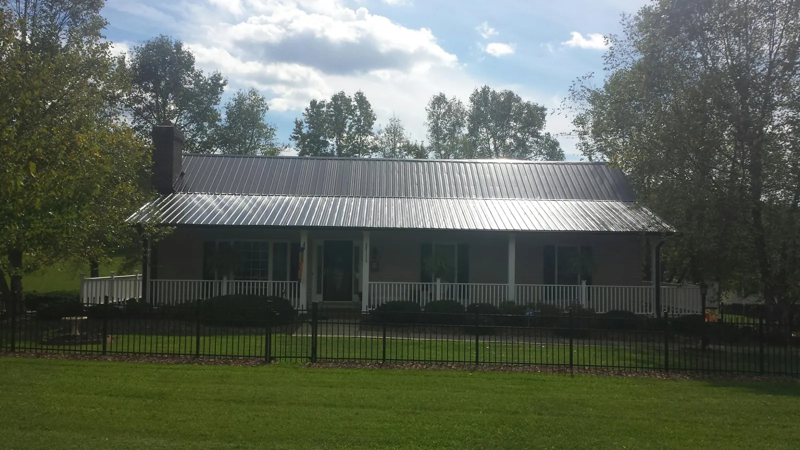 Gray metal roof on a brick ranch with a full width front porch — Gutter Guard Installation work by our crew in Blairsburg