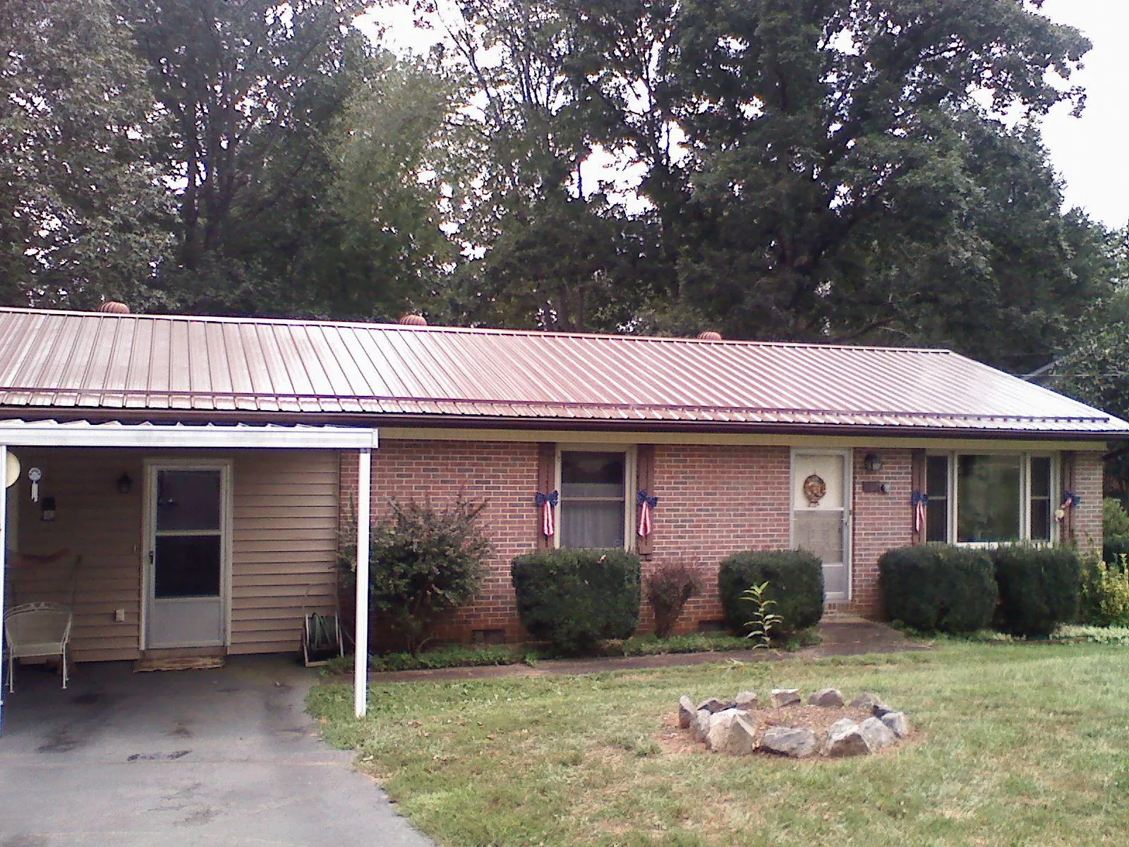 Bronze metal roof and carport on a brick ranch home — Roof Repair work by our crew in Blairsburg