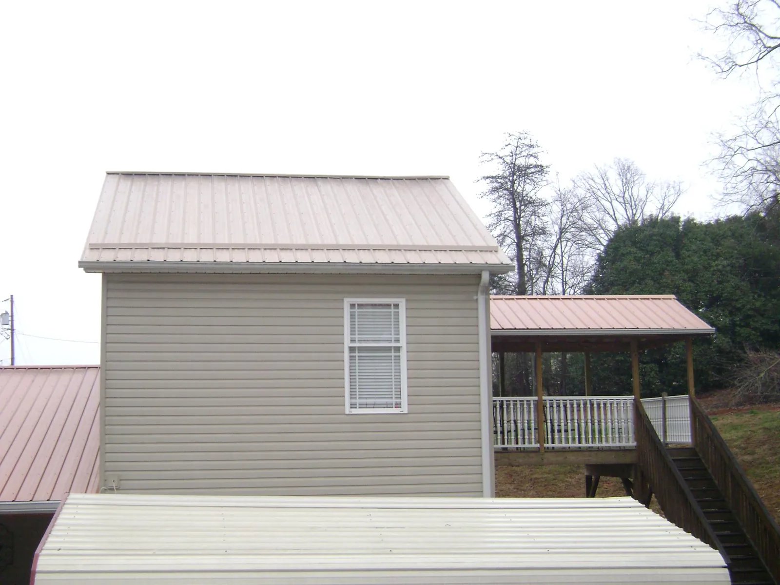 Tan metal roofs on a two story addition and attached porch, from a Roof Replacement job in Blairsburg