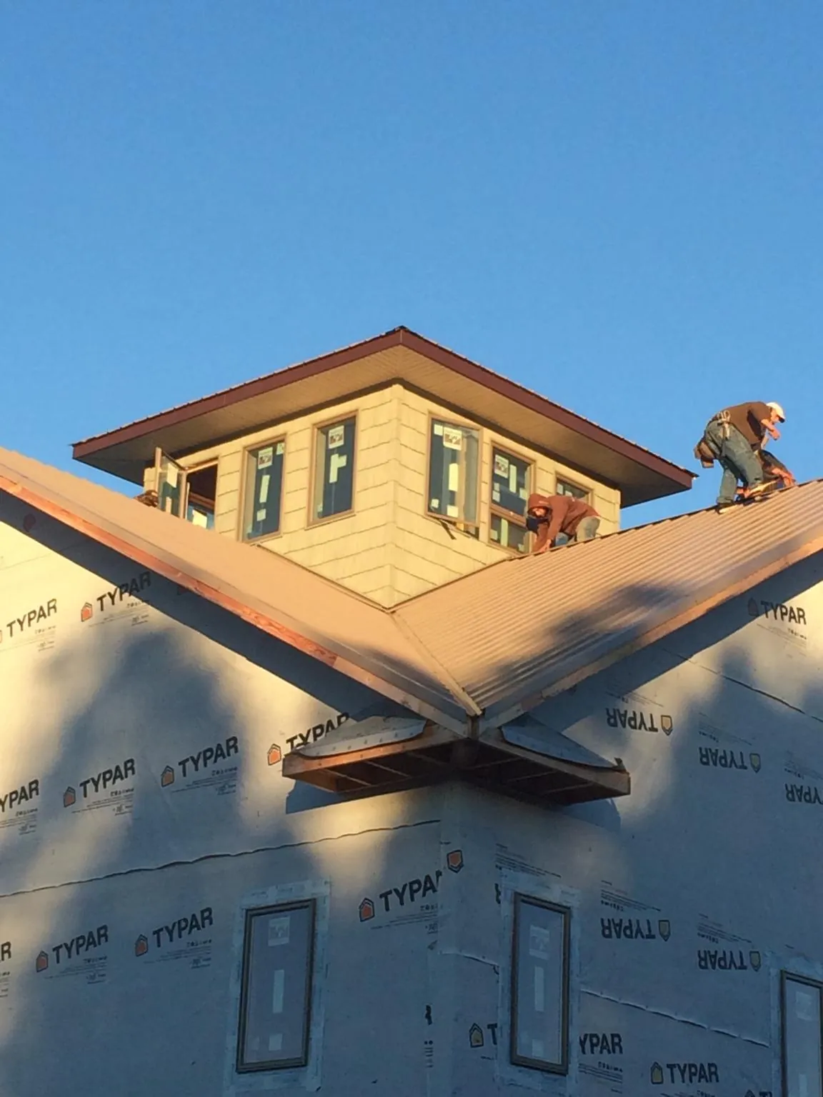 Roofers working around a rooftop cupola on a new metal roof at sunset — Roof Waterproofing in Blairsburg by Roofing Brothers